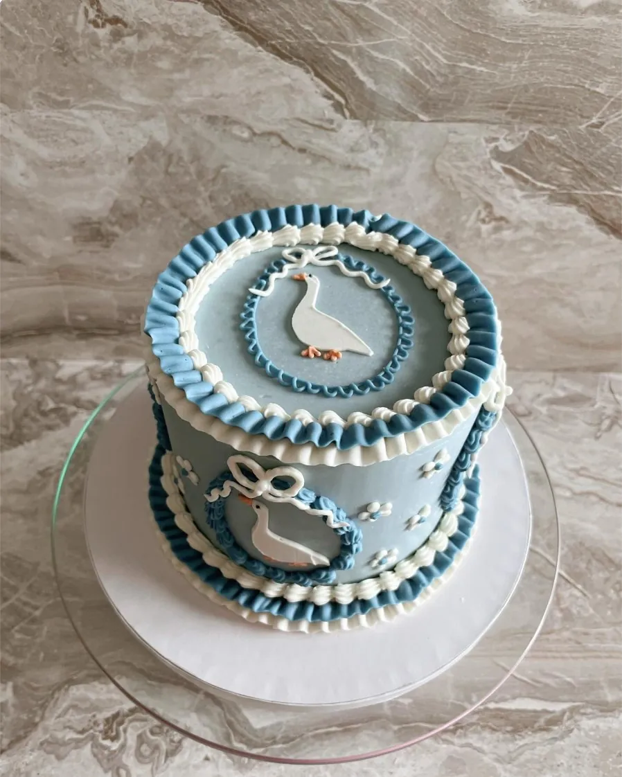 Dusty blue cake with ruffled piping and white goose details