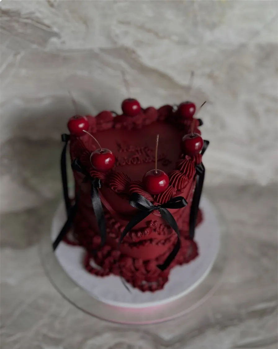 Deep red vintage heart cake with piped ruffles, cherries and black satin bows, made in Ocala, FL