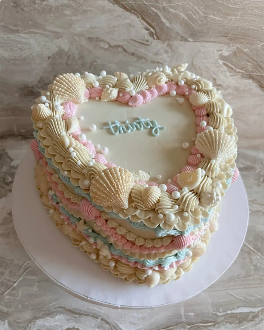 Ivory 30th birthday heart cake with buttercream seashells, pearls and pastel piping